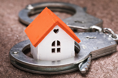 Tiny white and orange house sitting in handcuffs.